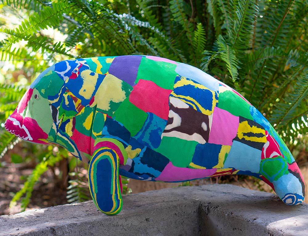 Large hand-carved multicolored manatee sculpture made of upcycled flip flops by Ocean Sole.